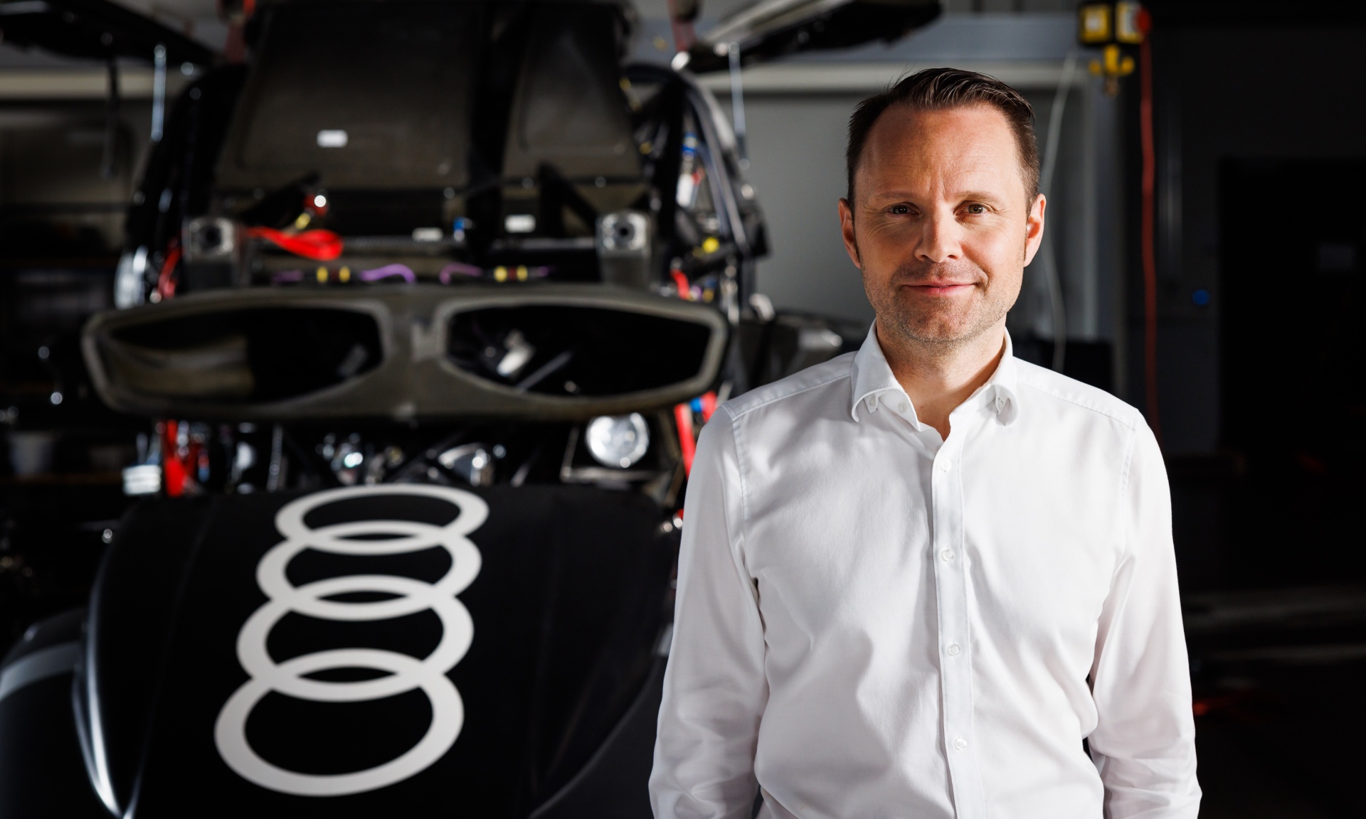 Rolf Michl in front of the vehicle parts of an Audi RS Q e-tron.