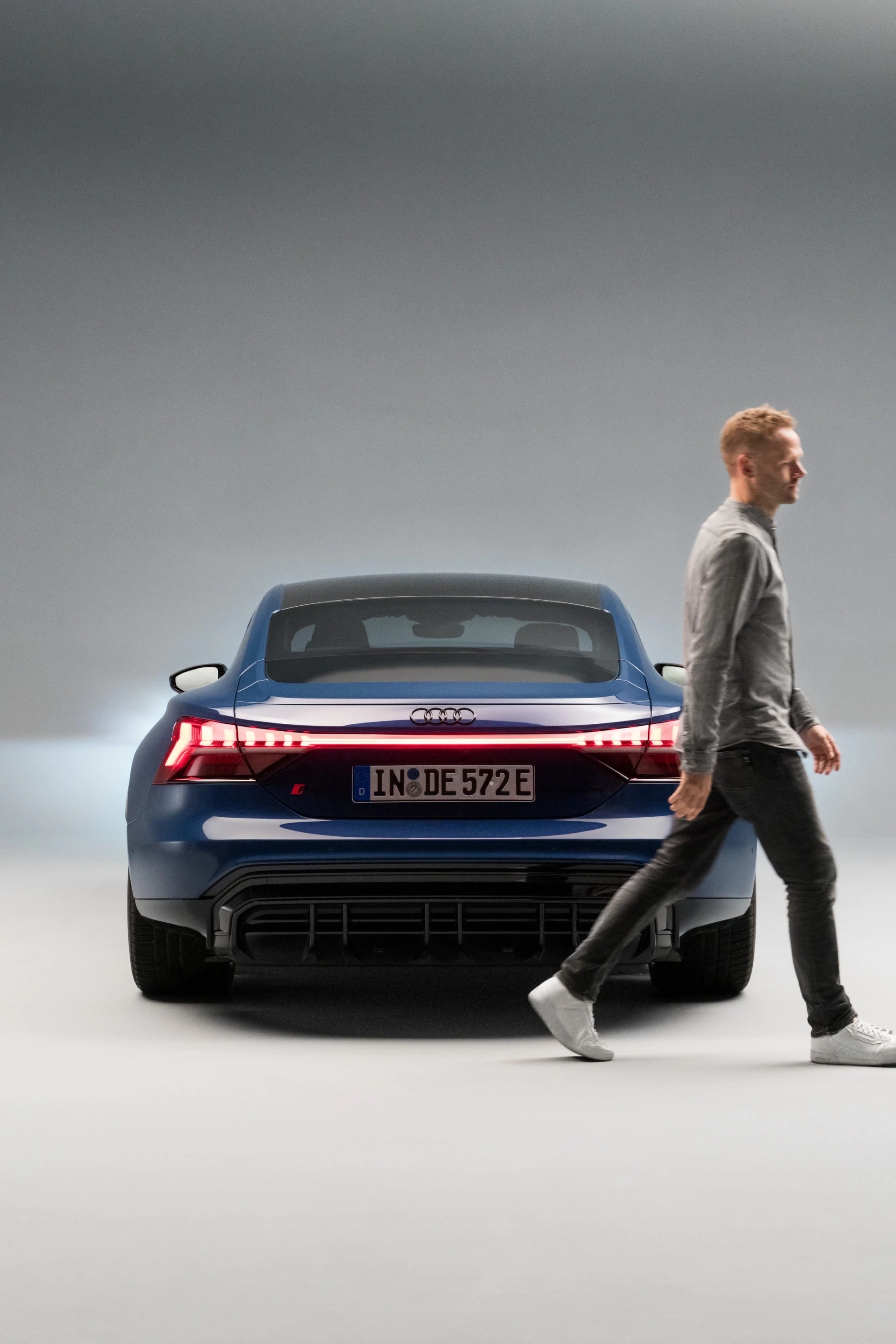 Christopher walking out of the picture alongside the rear of the Audi RS e-tron GT{ft_rs-e-tron-gt}.